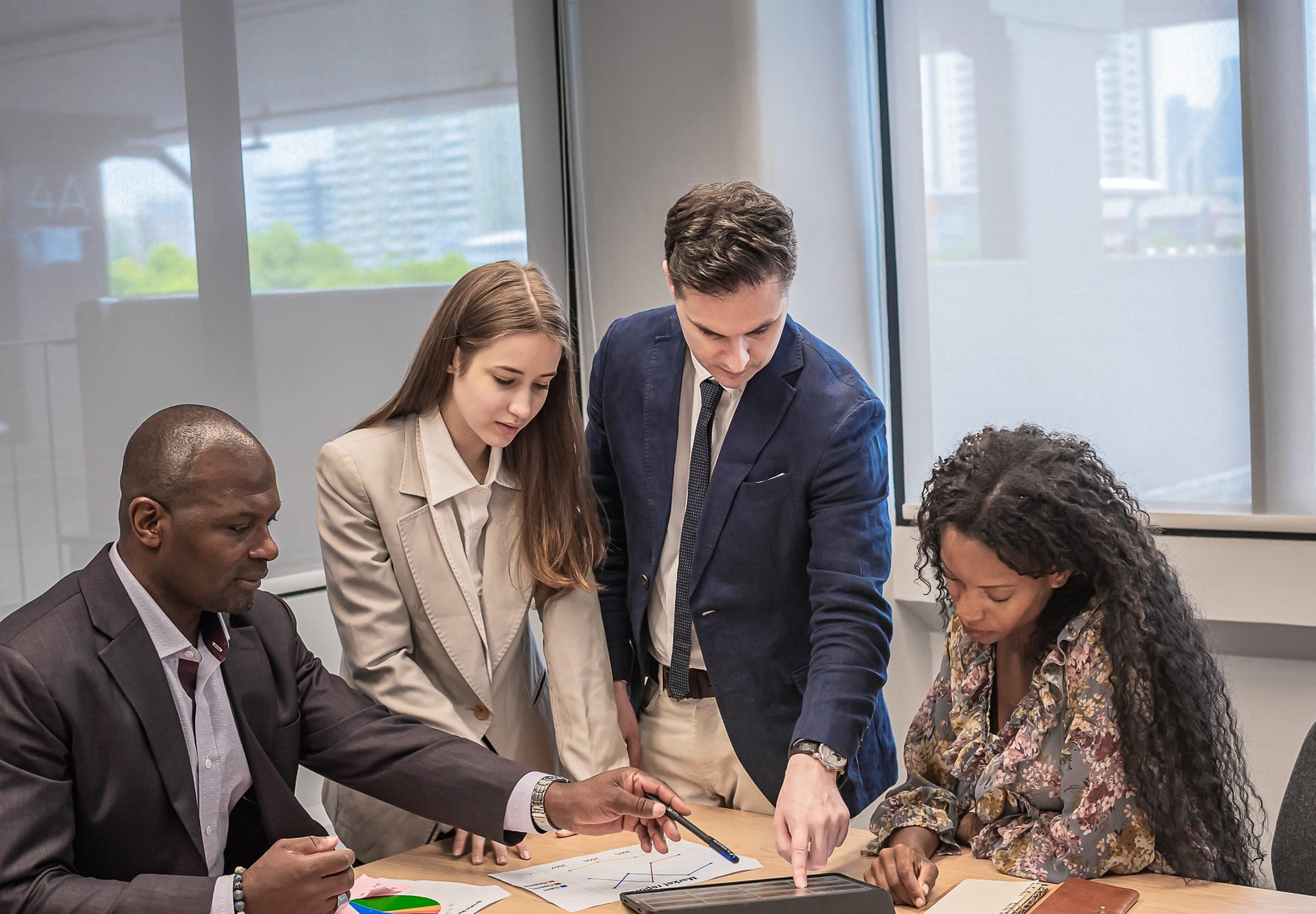 Senior leaders in discussion around a table in a glass-walled boardroom