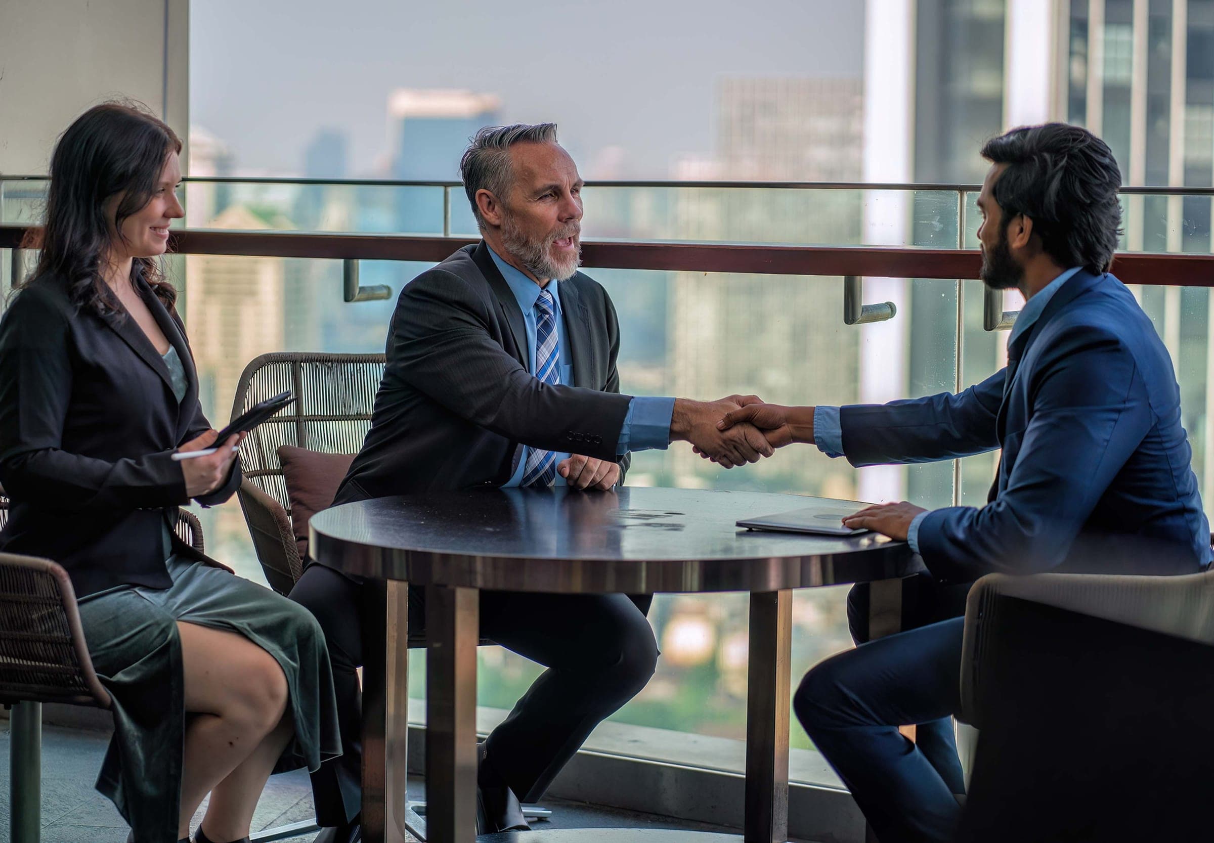 Two executives shaking hands, a city skyline showing through the frame