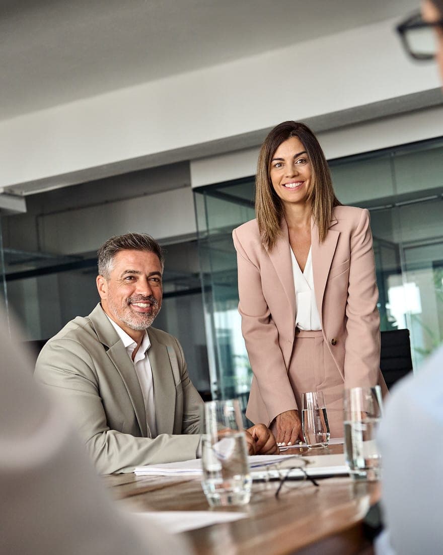 Smiling business woman and man at a boardroom table, Adastrum Consulting discussion